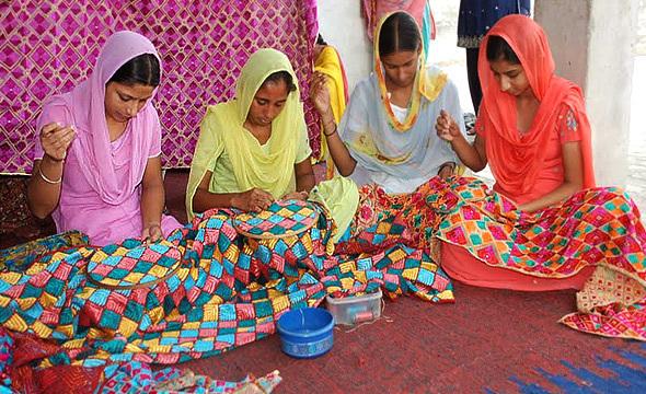 Image of four women embroidering a tradition Punjabi scarf known as the "Phulkari dupatta".
